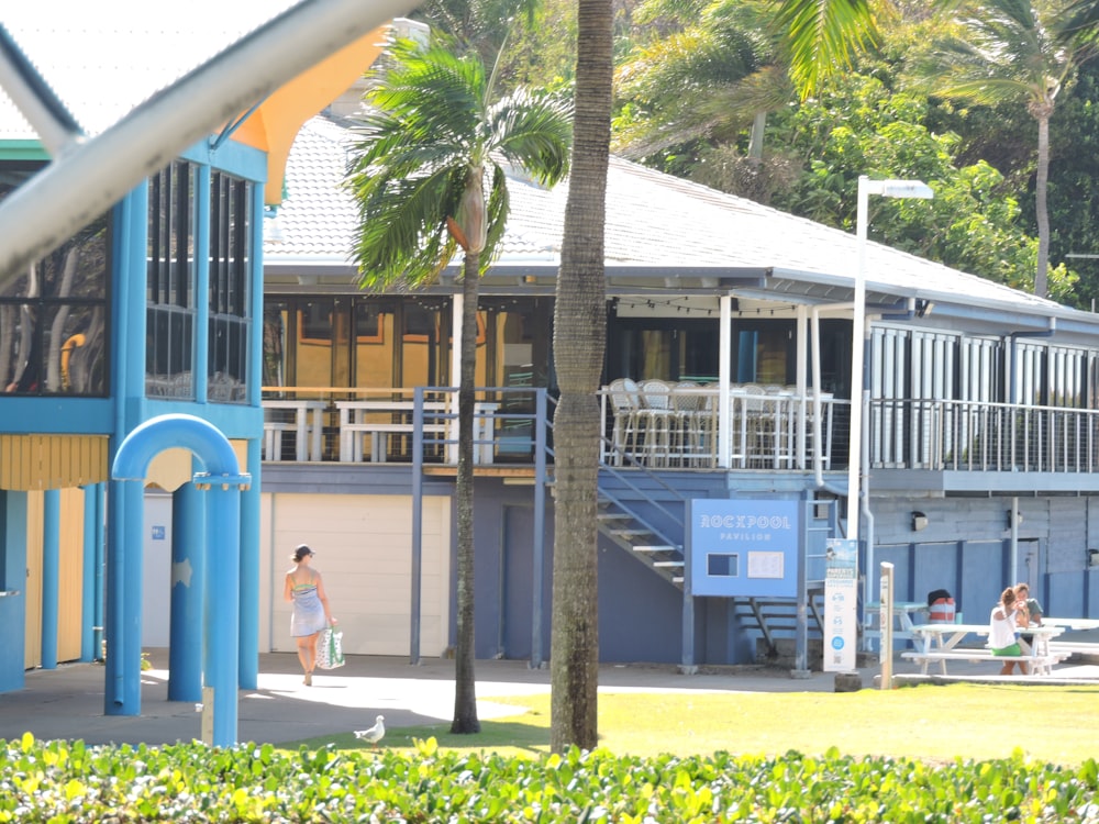 a woman walking past a blue and yellow building