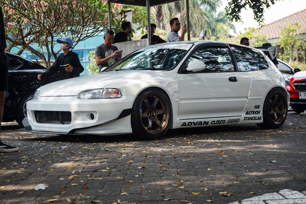 a white car parked in front of a group of people