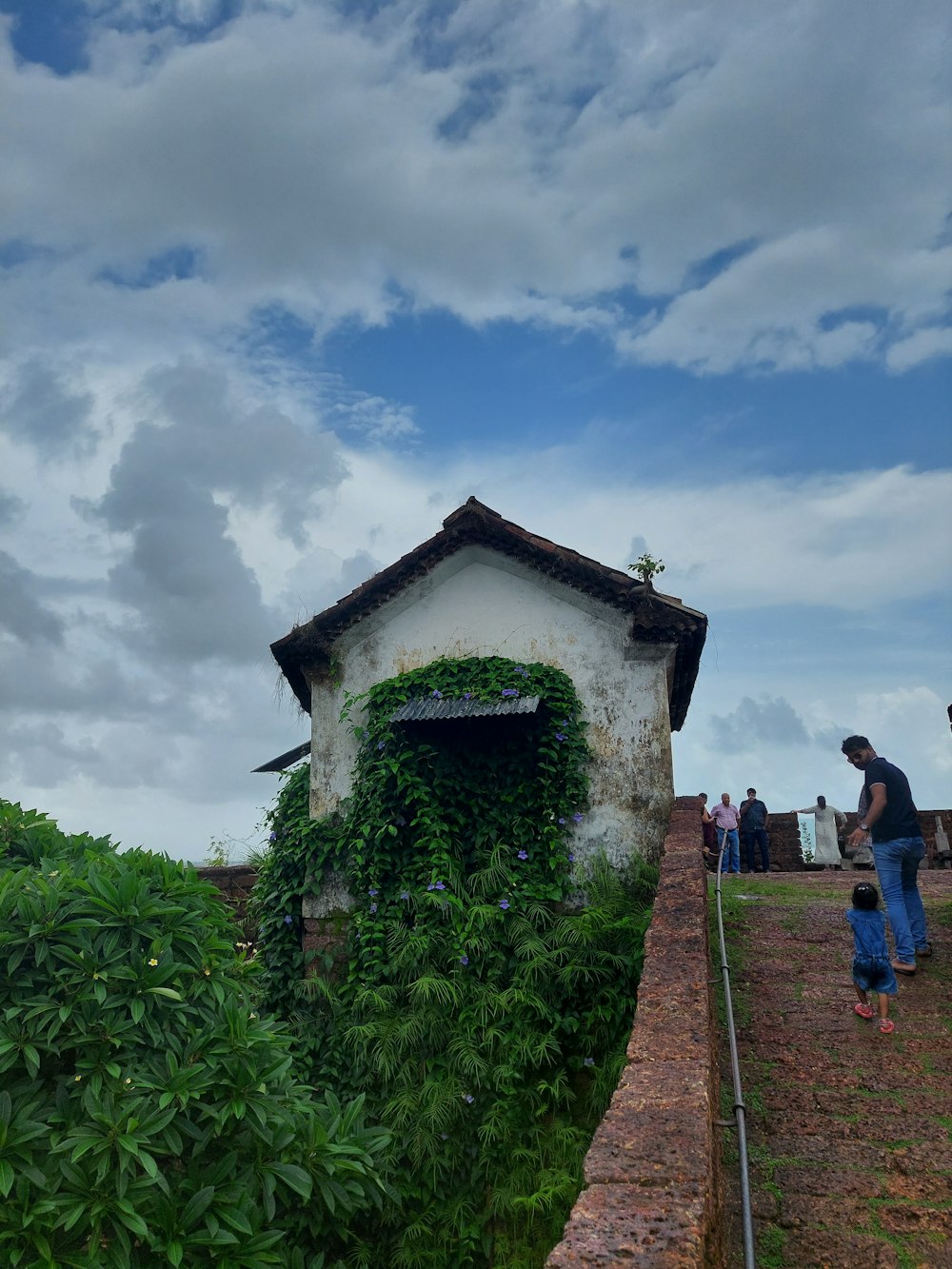 a man standing next to a building covered in vines