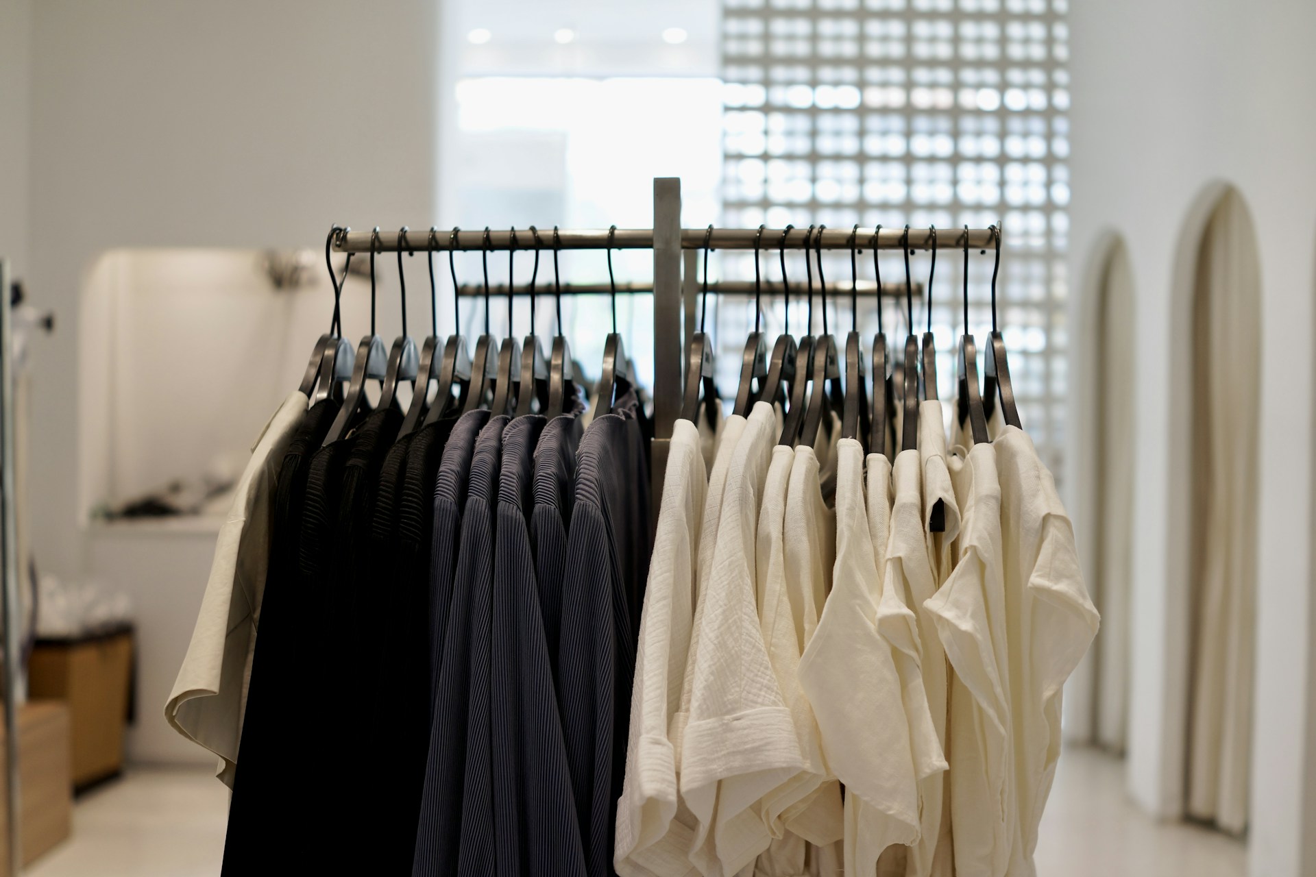A close-up of a neatly arranged clothing rack featuring trendy, minimalistic apparel in soft, neutral colors.