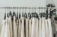 Artistic black and white image of a cover-up hanging on a sleek modern rack with warm beige wall in background.