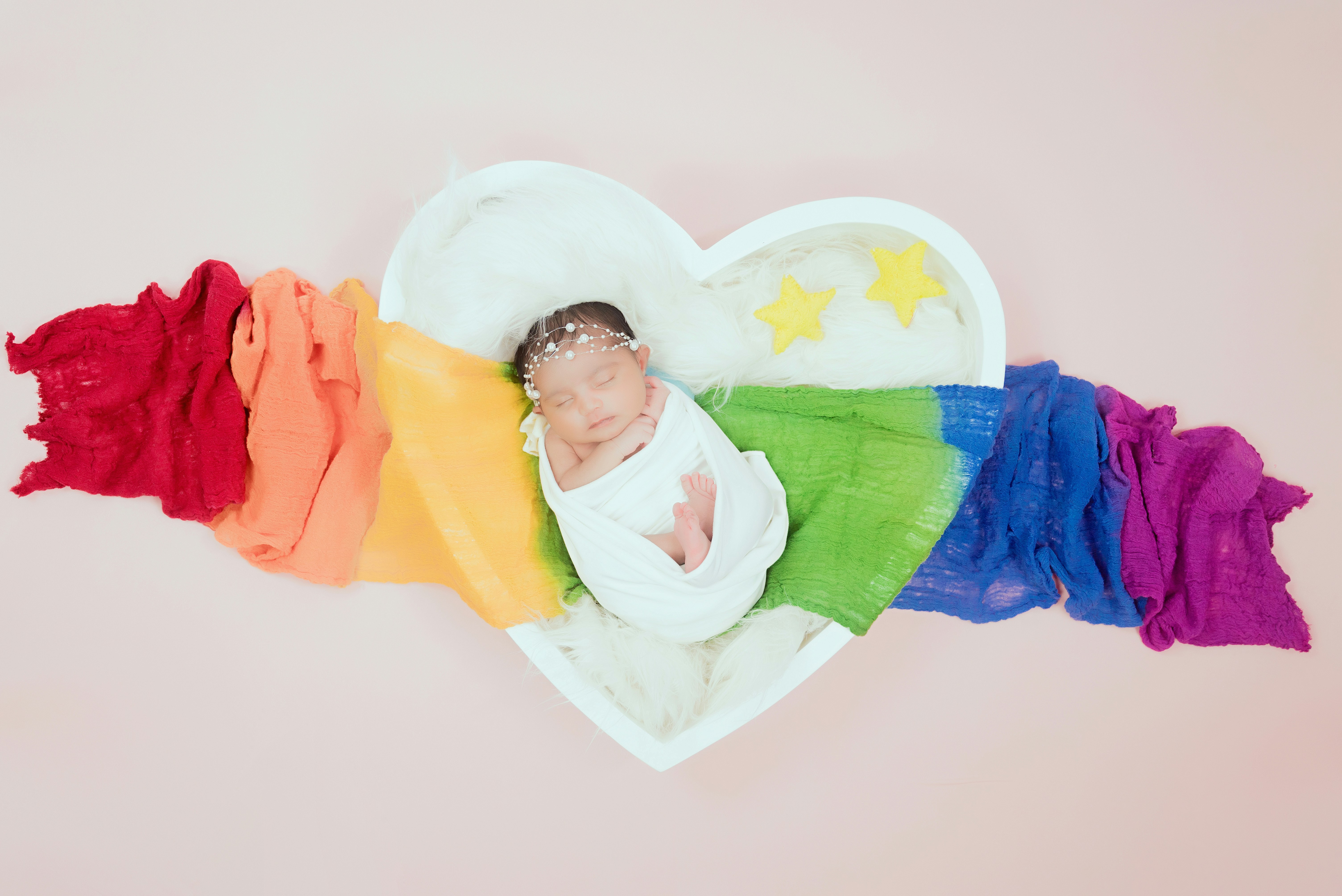Colorful rainbow crochet baby blanket on white bed