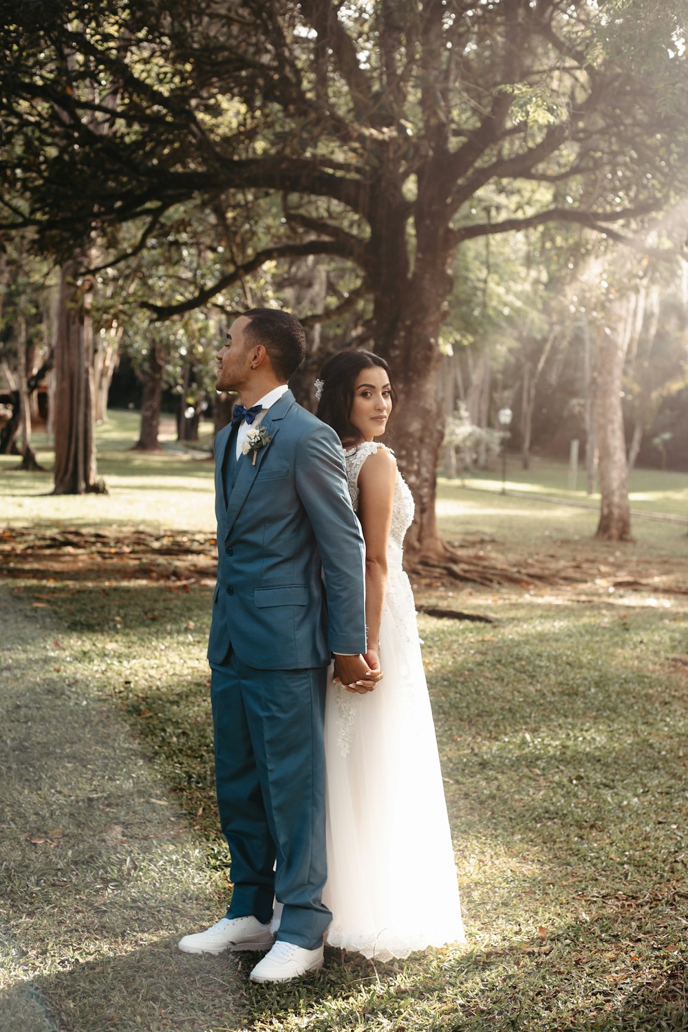 Braut und Bräutigam, die im Gras unter einem Baum stehen