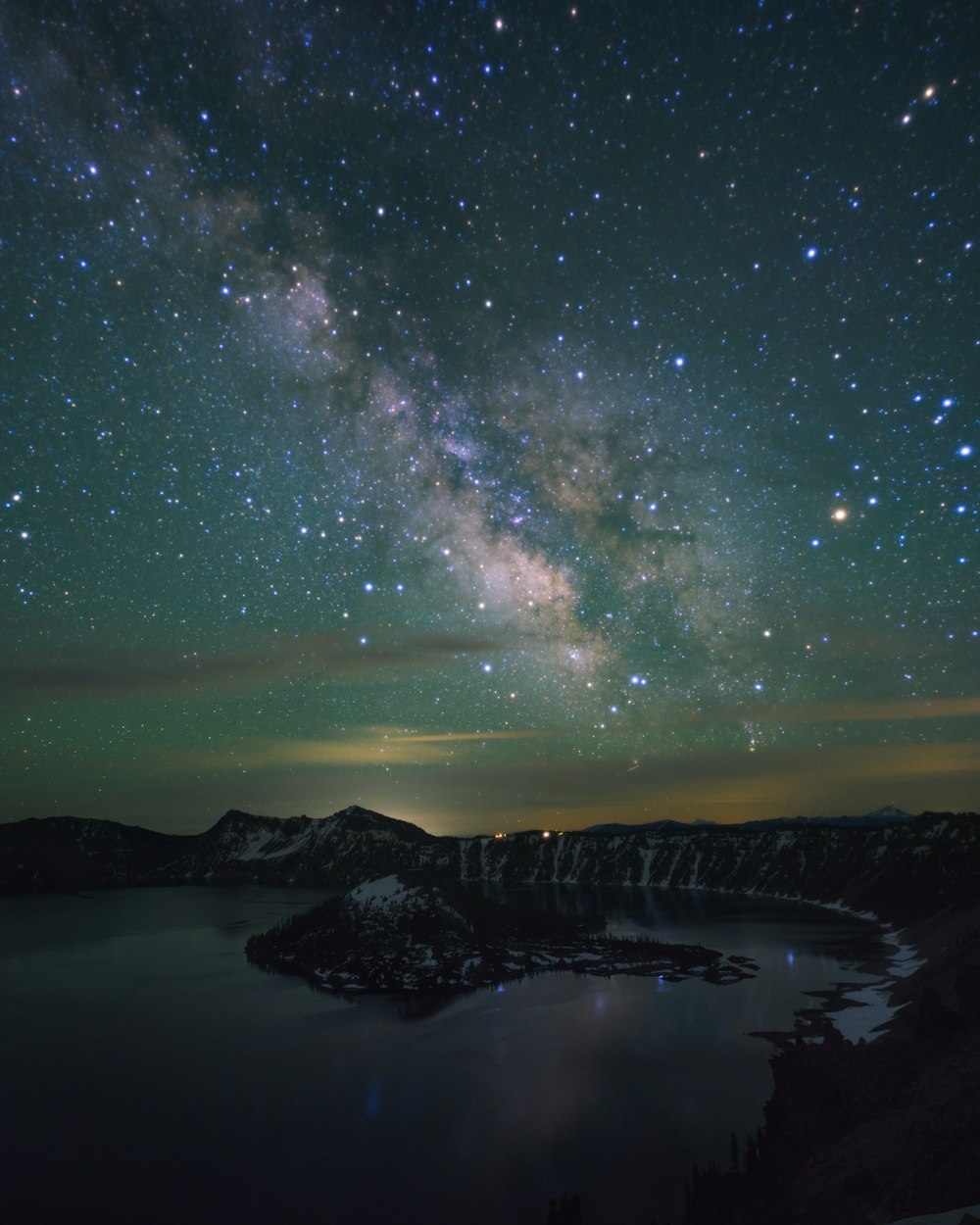 the night sky with stars above a lake