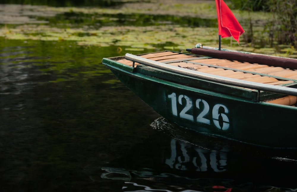 a small green boat with a red flag in the water