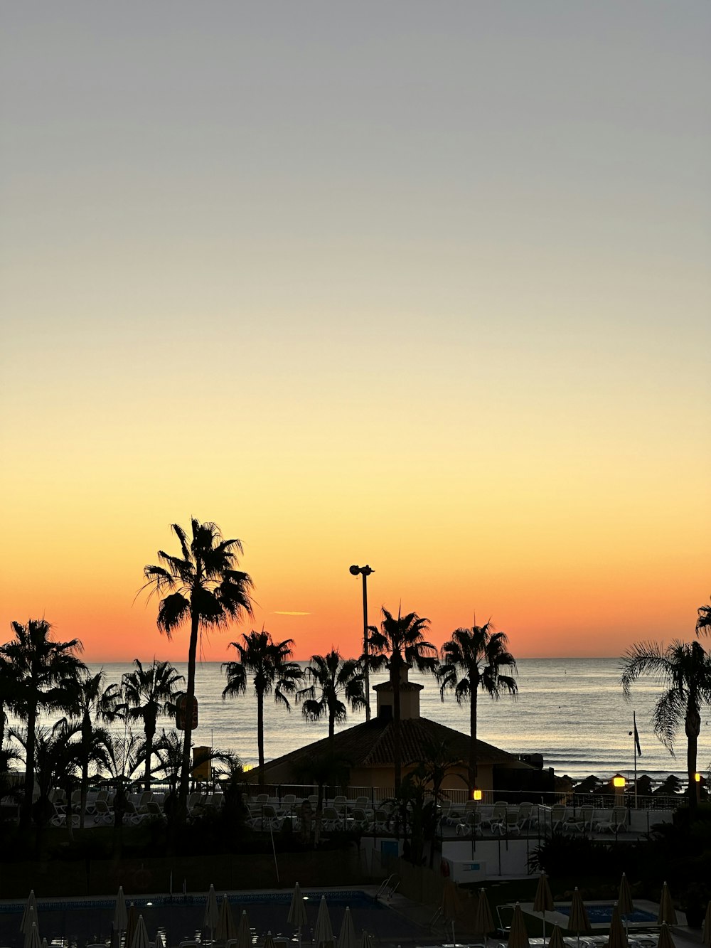 a sunset view of a beach with palm trees