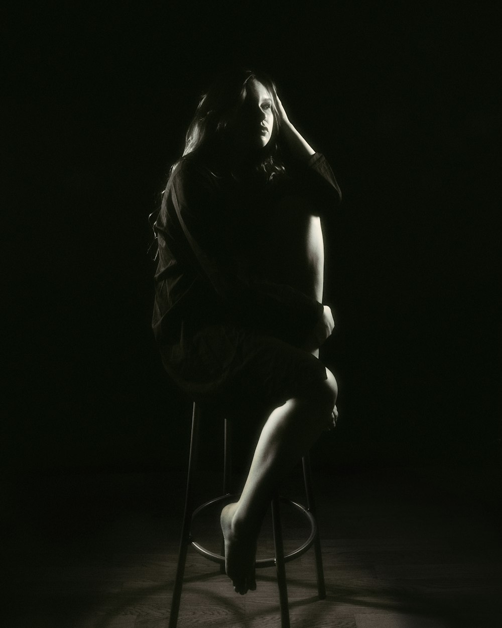 a black and white photo of a woman sitting on a stool