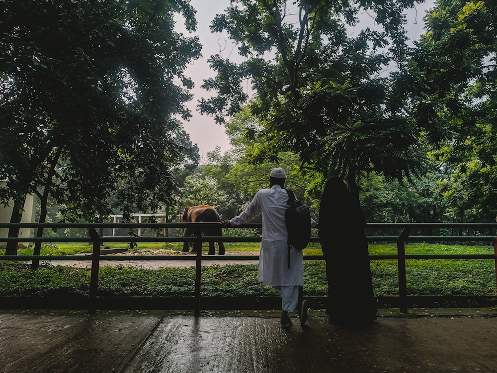 a man standing next to a horse on a lush green field