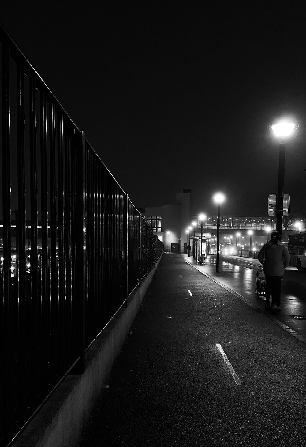 a black and white photo of a person walking down a street at night