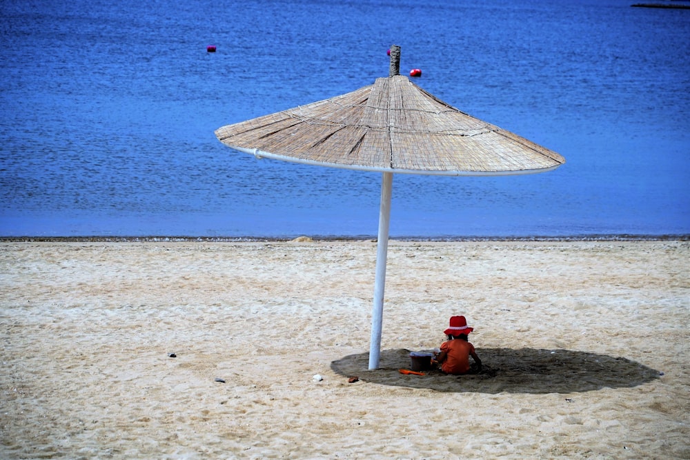 a red fire hydrant sitting under an umbrella on a beach