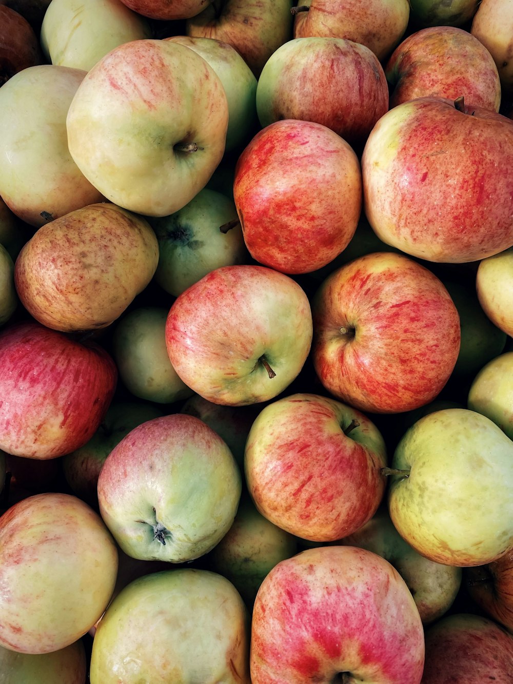 a pile of red and green apples sitting on top of each other