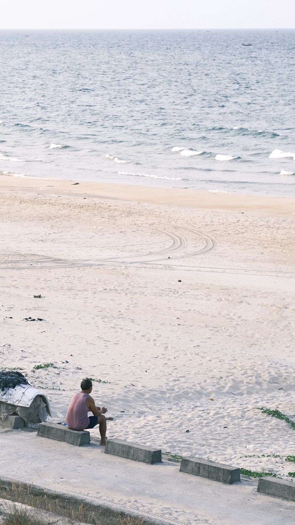 a person sitting on a concrete ledge near the ocean