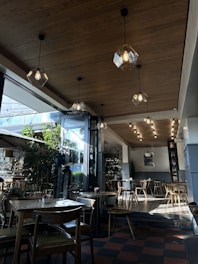 Interior of a cozy café featuring wooden tables, soft pendant lights, and comfortable seating.