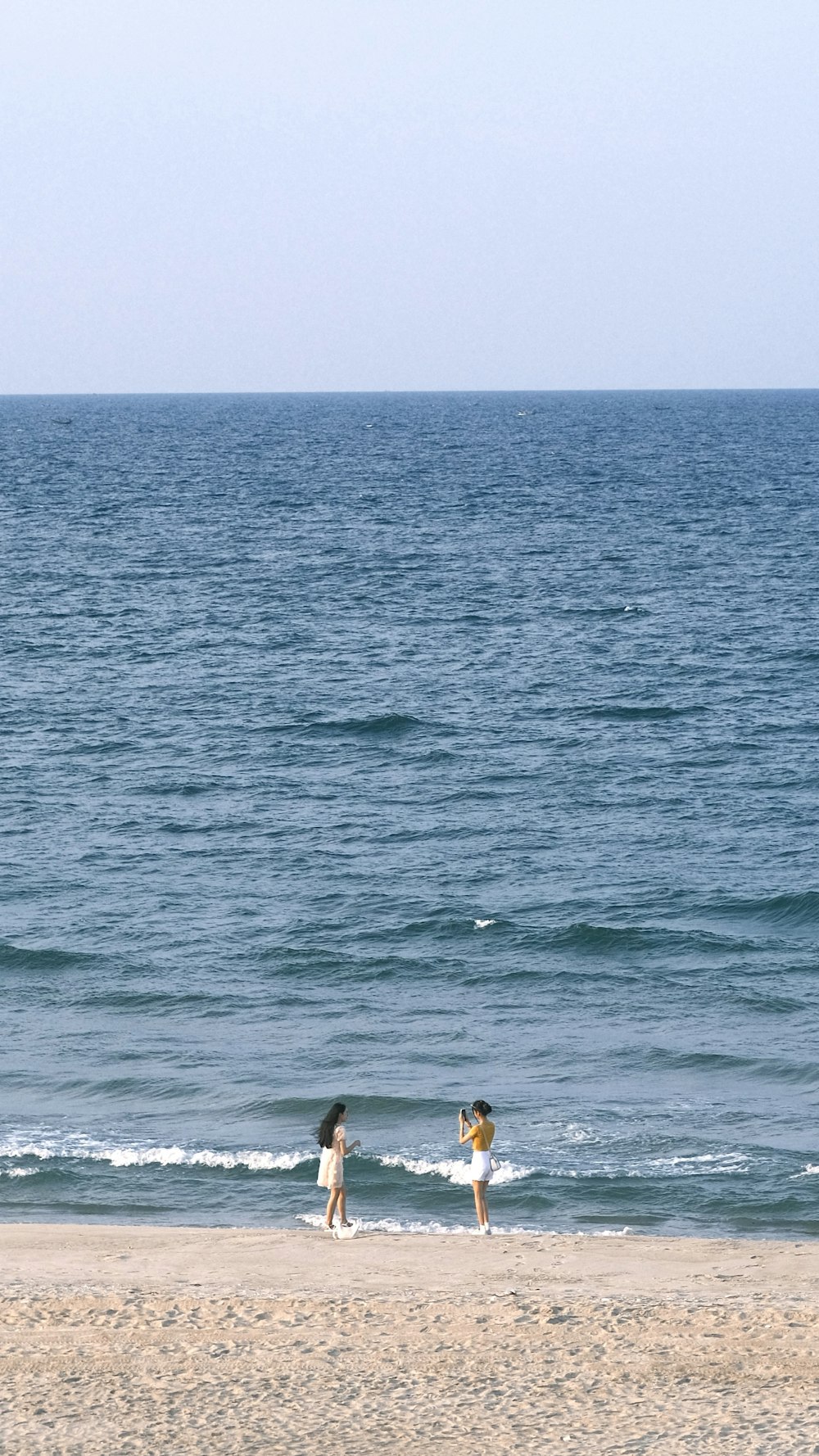 a couple of people standing on top of a sandy beach