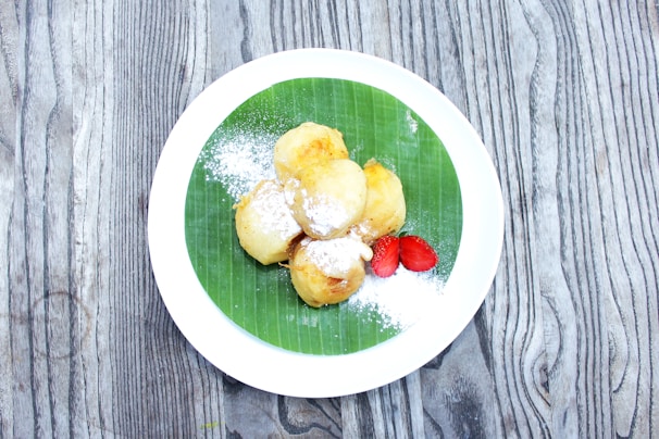 Serving of banana chips and sarkaravaratti on a palm leaf plate.