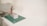 Someone wearing a striped sweater is using a screwdriver to fix or assemble a rectangular object with light blue and purple patterns on its side. The object is placed on a green cutting mat, situated on a white surface or table.