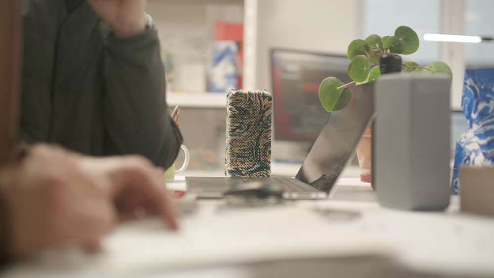 a person writing on a piece of paper next to a plant