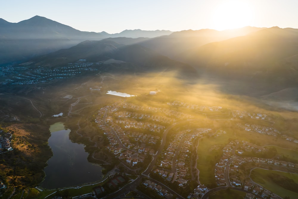 an aerial view of a city with a lake and mountains in the background