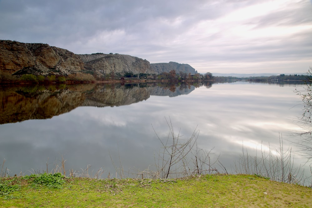 a large body of water surrounded by a lush green field