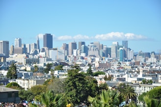 A vibrant city skyline with diverse residential and commercial buildings under a clear sky.