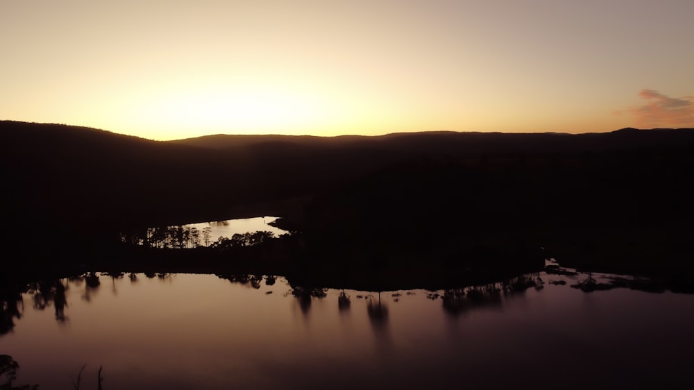 the sun is setting over a lake in the mountains