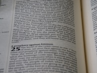 Open pages of a book in close-up showing text. The visible text includes numbered sections and is formatted with italicized and bold fonts in parts. The paper appears slightly off-white and the text is printed in black ink.