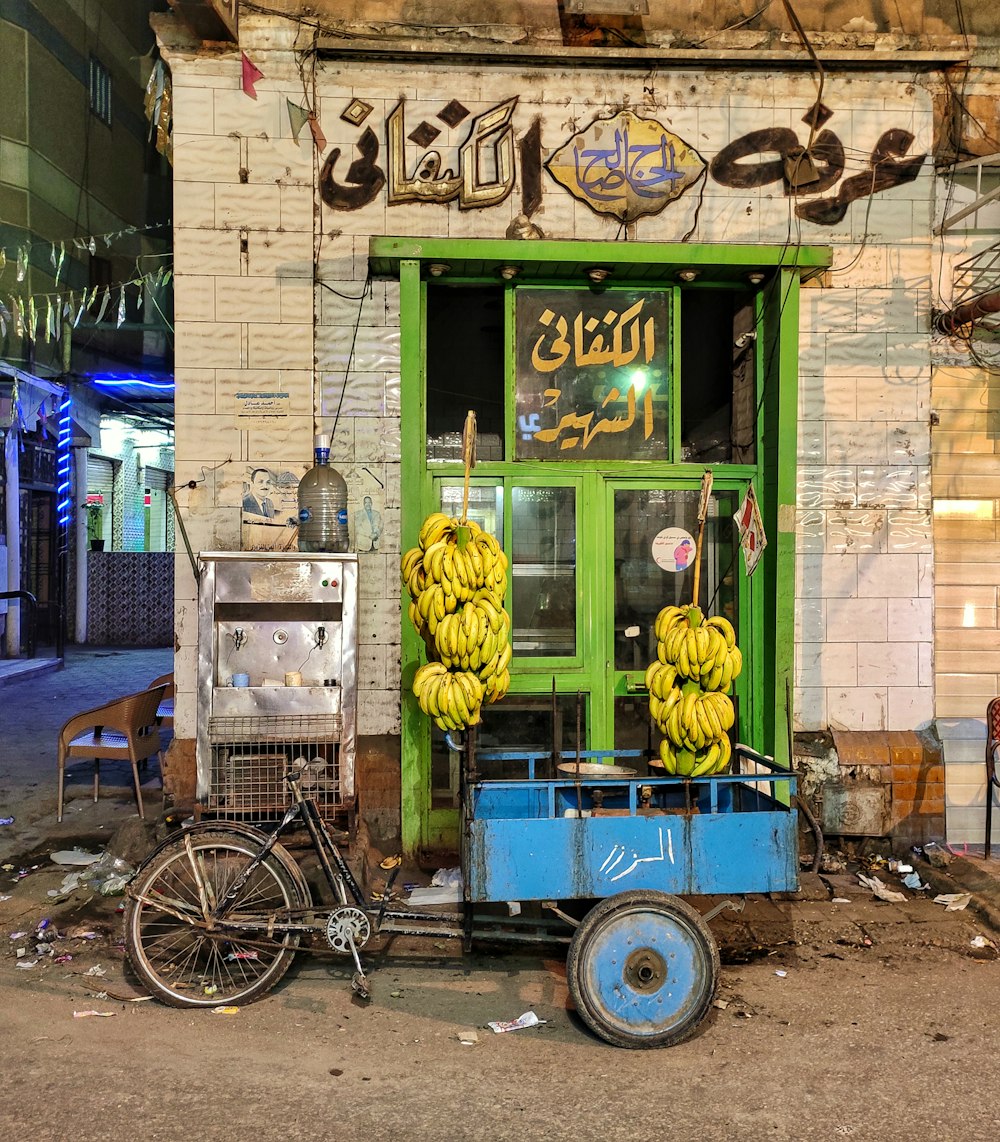 a bicycle parked in front of a store with bunches of bananas