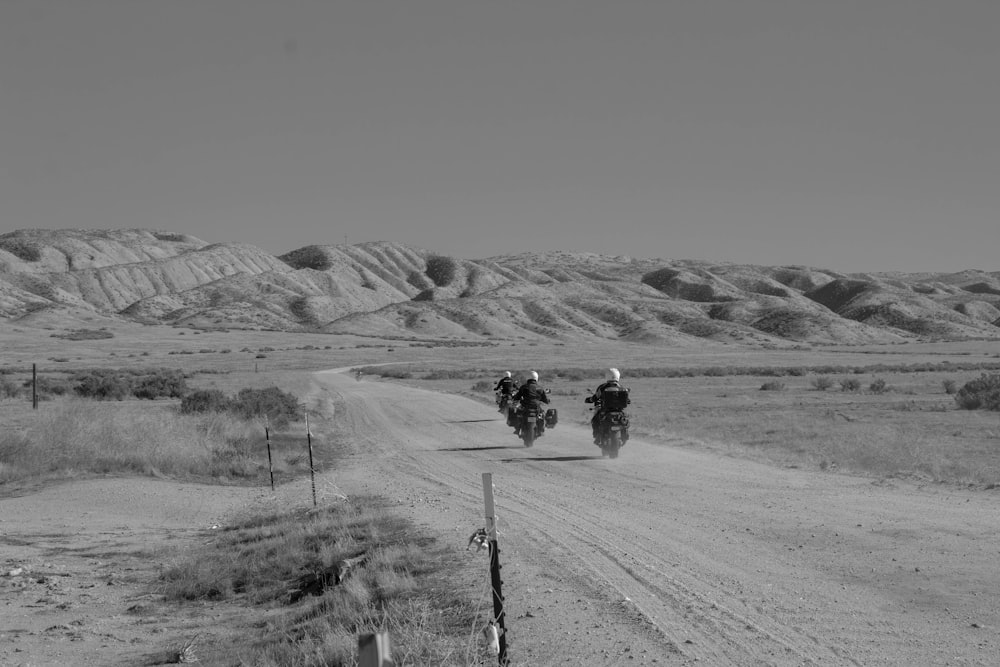 two people riding motorcycles down a dirt road