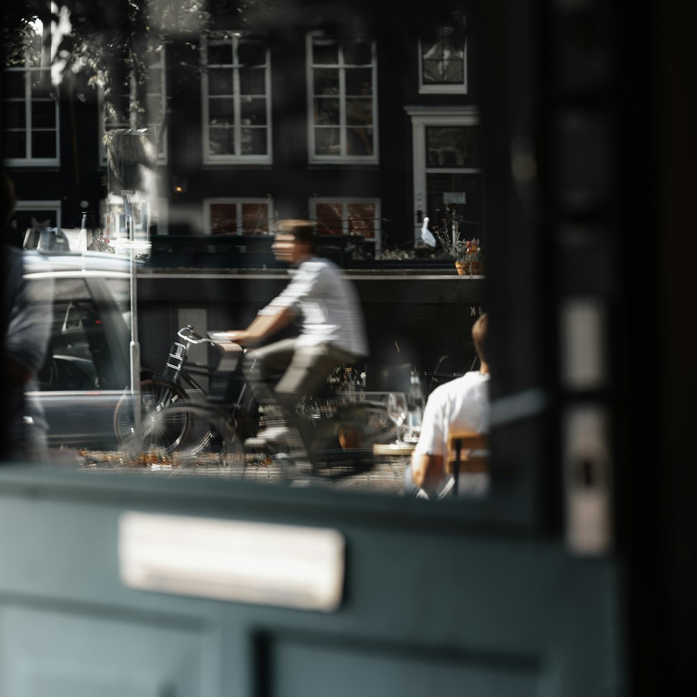 Un reflejo de un hombre montando una bicicleta en una ventana