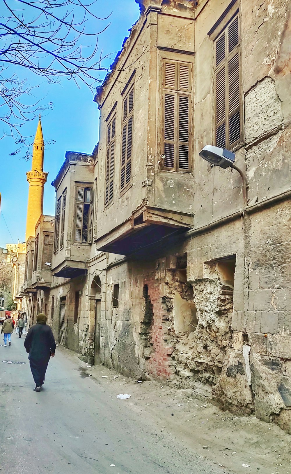 a person walking down a street next to a tall building