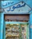 An old shop facade with Arabic writing at the top. The storefront display is filled with an assortment of wristwatches and various small, colorful boxes or packaging. The exterior has peeling blue paint, giving it a vintage and worn-out appearance.