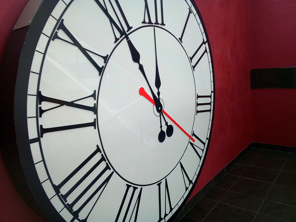 une grande horloge sur un mur rouge dans une pièce
