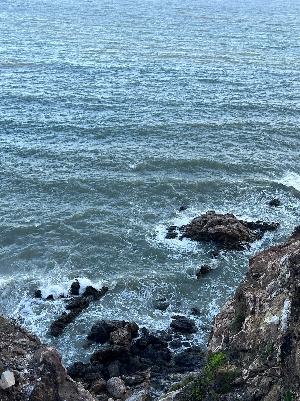 a man sitting on top of a rock next to the ocean