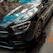 Close-up shot of a sleek black luxury car with a glossy finish reflecting city lights at night.