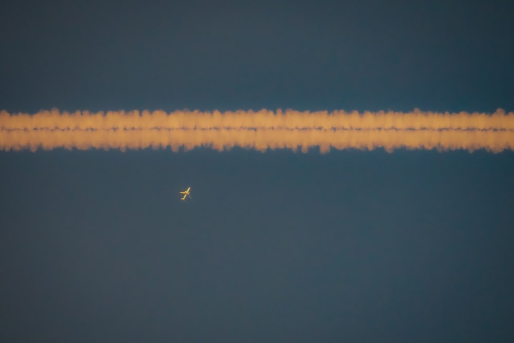 a plane is flying in the sky with a long strip of smoke behind it