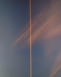a plane flying in the sky with a contrail