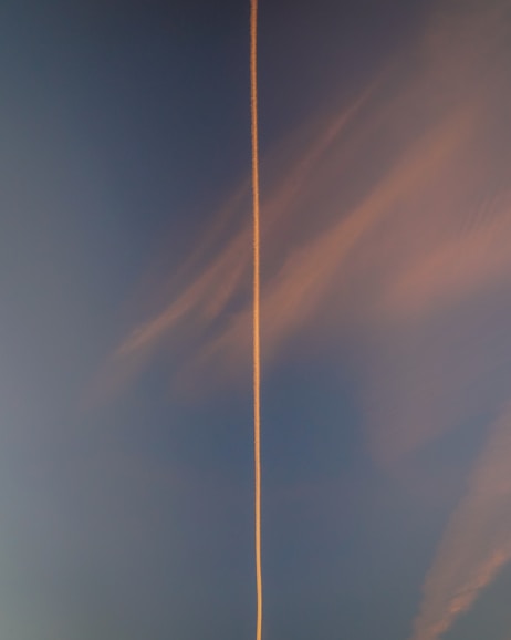 a plane flying in the sky with a contrail