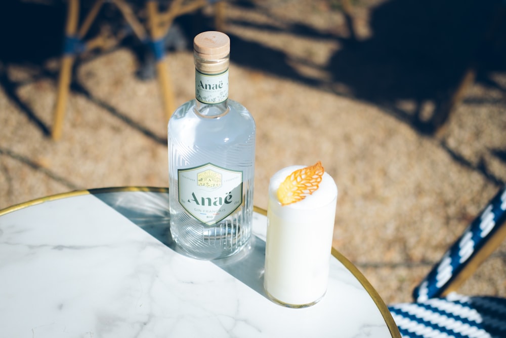 a bottle of alcohol sitting on top of a table next to a glass