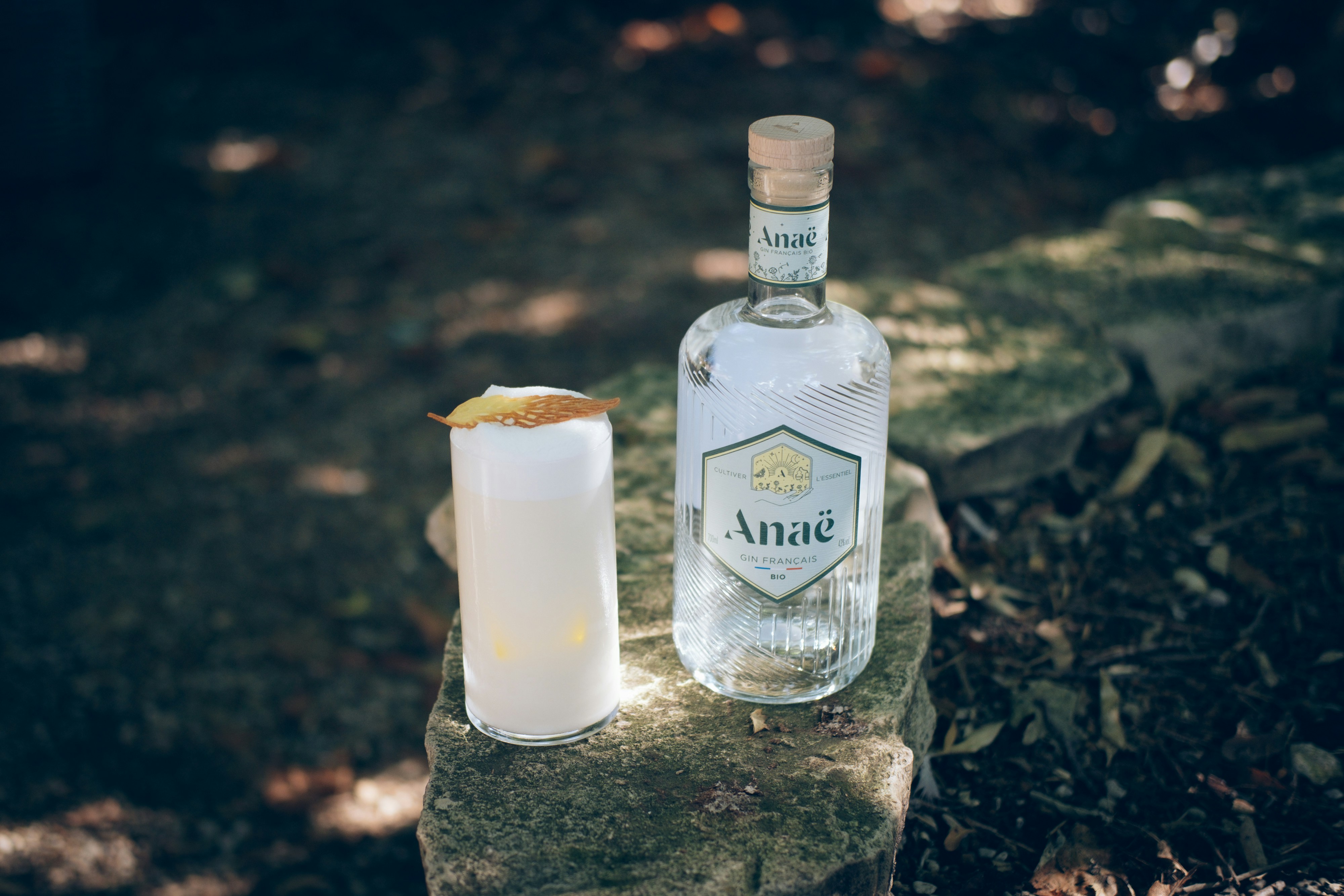 a bottle of alcohol next to a glass on a rock