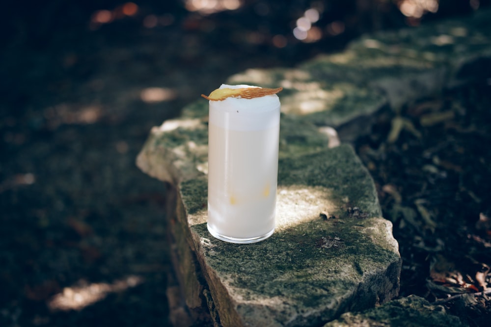 a glass of milk sitting on top of a rock