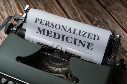 A vintage typewriter with a sheet of paper that has the words 'PERSONALIZED MEDICINE' typed in bold letters. The typewriter is placed on a rustic wooden surface, giving a classic and nostalgic feel.