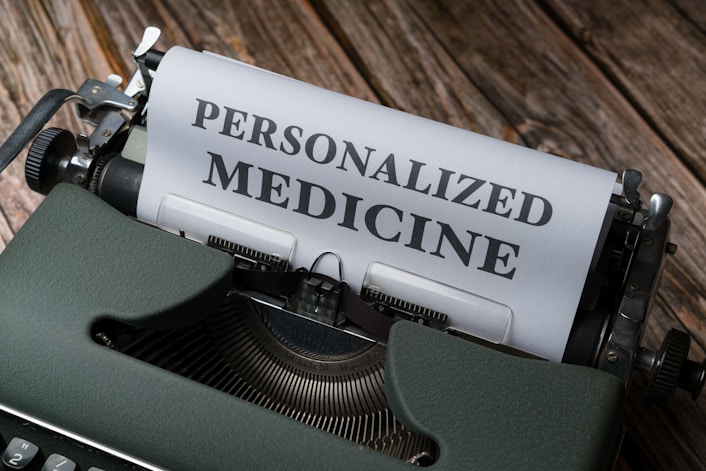 A vintage typewriter with a sheet of paper that has the words 'PERSONALIZED MEDICINE' typed in bold letters. The typewriter is placed on a rustic wooden surface, giving a classic and nostalgic feel.