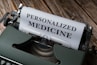 A vintage typewriter with a sheet of paper that has the words 'PERSONALIZED MEDICINE' typed in bold letters. The typewriter is placed on a rustic wooden surface, giving a classic and nostalgic feel.