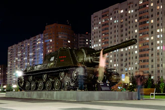 A sleek, high-tech military tank rolling through a digital battlefield with camouflage patterns blending into a futuristic cityscape.