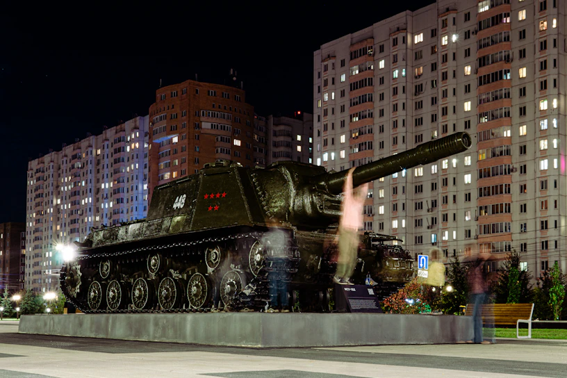 A sleek, high-tech military tank rolling through a digital battlefield with camouflage patterns blending into a futuristic cityscape.