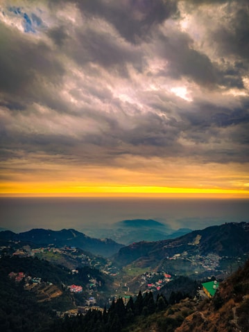 a scenic view of a valley and mountains under a cloudy sky