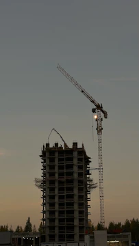 Evening shot of Ikhwan Tower under construction with cranes and workers.