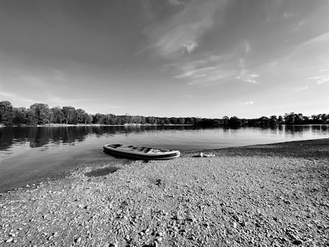 A serene lake at dawn with an inflatable kayak gently floating near the shore.