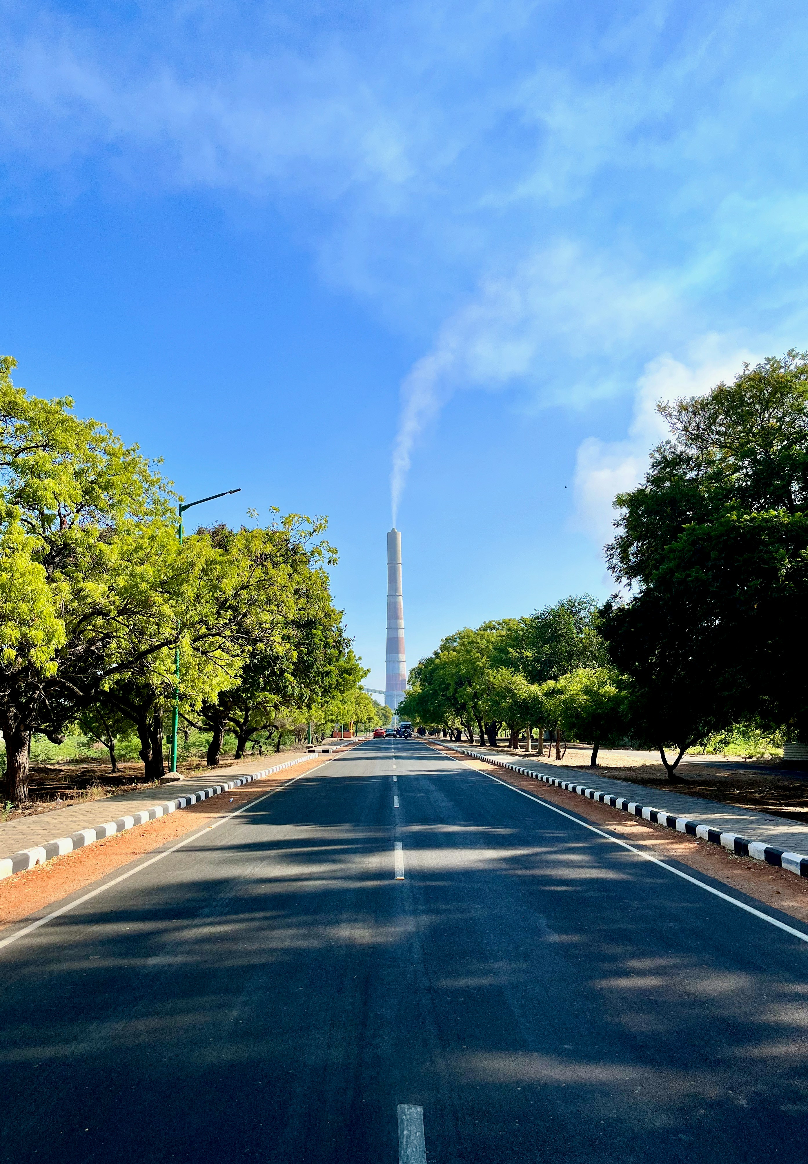 a long empty road with a tall tower in the background