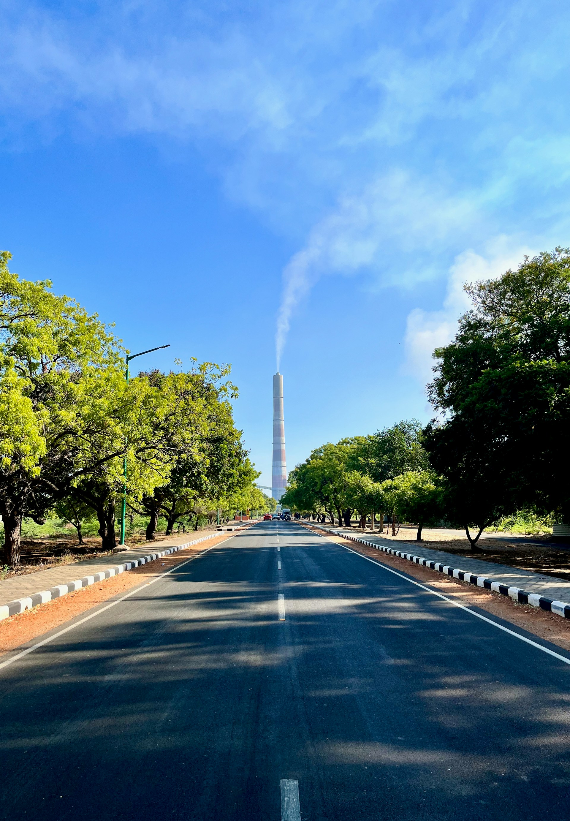 a long empty road with a tall tower in the background